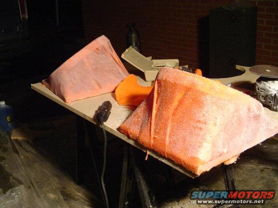 Orange foam car body parts on a workbench with tools