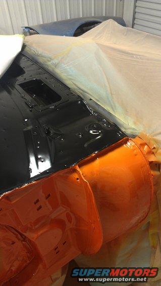 Car body parts with black and orange paint, covered in plastic sheeting