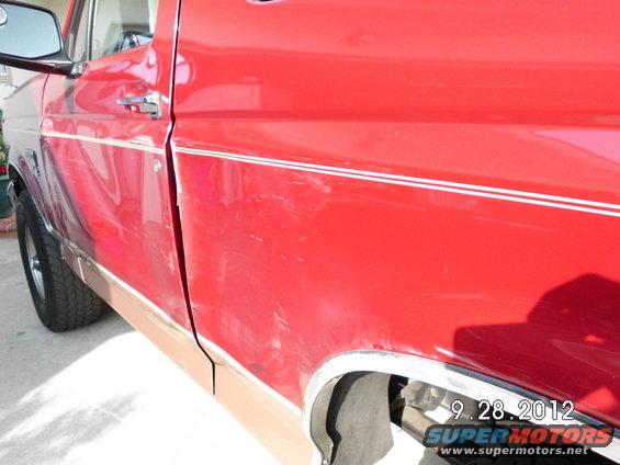 Side view of a red pickup truck with a tan lower body panel and chrome trim. The paint has numerous scratches
