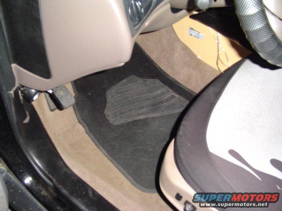Interior view of driver's side floor with pedals and floor mat