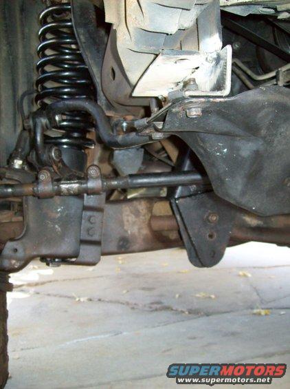 close-up of truck's front suspension, showing coil spring, sway bar, and steering linkage