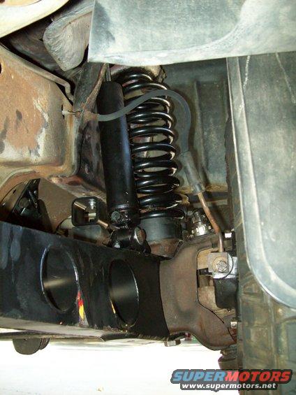 Close-up of a black coil spring and shock absorber assembly on a truck's suspension