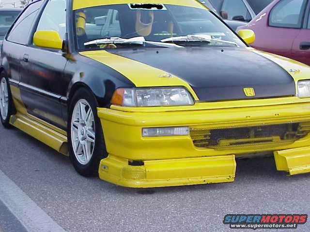 Yellow and black Honda Civic hatchback with aftermarket body kit and silver wheels, front 3/4 view