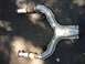 1996 Ford Bronco - An exhaust pipe with flexible connectors is shown laid out on asphalt.