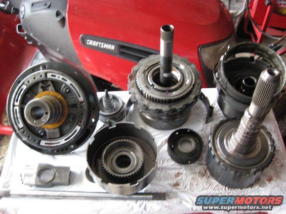 Another View of the Parts.
From left to right (Top):
Pump assembly
Overdrive servo assembly
intermediate band
Intermediate clutches / reverse clutch / reverse one way clutch/ forward clutch assembly
Reverse Band and Planetary Gearset

From left to right (Bottom):
Governer assembly
Direct drive shaft
Drive shell
sun gear
Direct drive clutch and output shaft assembly
