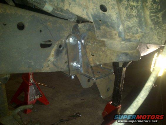Custom suspension bracket welded to vehicle frame, supported by jack stands
