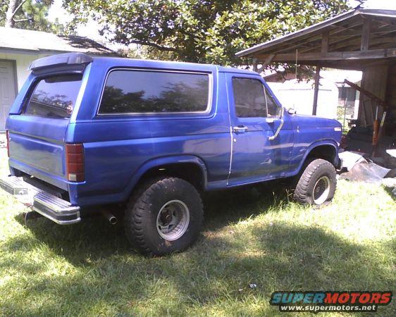 Blue SUV parked on grass next to a wooden structure