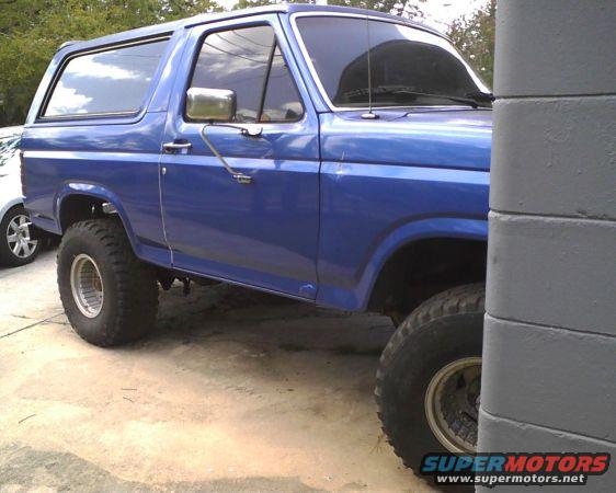 Blue Ford Bronco with lifted suspension and large tires, parked outdoors