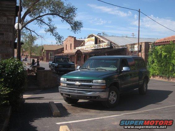 Green SUV parked in a lot with a dark pickup truck in the background