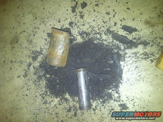 Two rusty metal pipe sections and dark debris scattered on a concrete floor