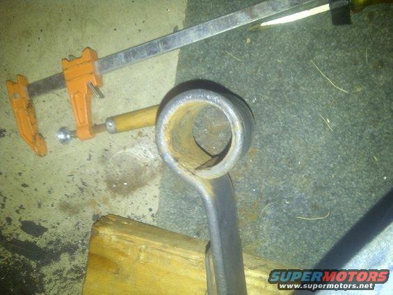 Pipe fitting held by clamp and wood block