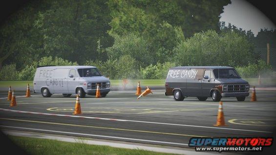 Two vans, one white and one dark gray, with 'FREE CANDY!!' and 'FREE CANDY' written on their sides, driving on a track with orange cones