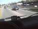 2003 Ford Crown Victoria - A dark sedan is seen from the driver's perspective with a large, furry object stuck to its rear bumper while driving on a road.