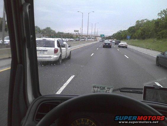 White minivan with open doors on a wet highway, viewed from inside a vehicle