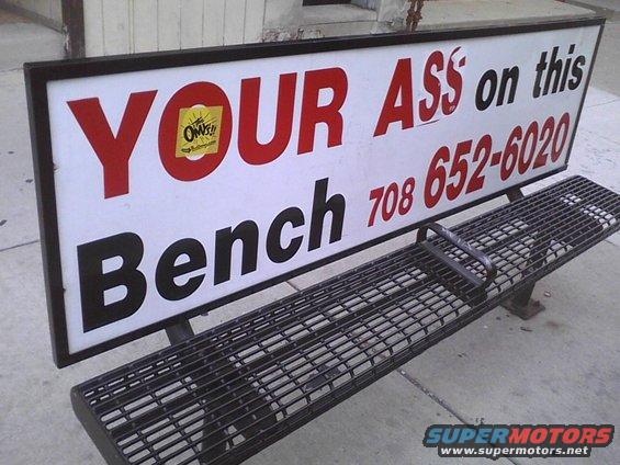 Bench with sign that says 'YOUR ASS on this Bench' and a phone number