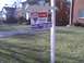 2003 Ford Crown Victoria - A real estate sign advertises a home for sale with agent contact details and a photo.