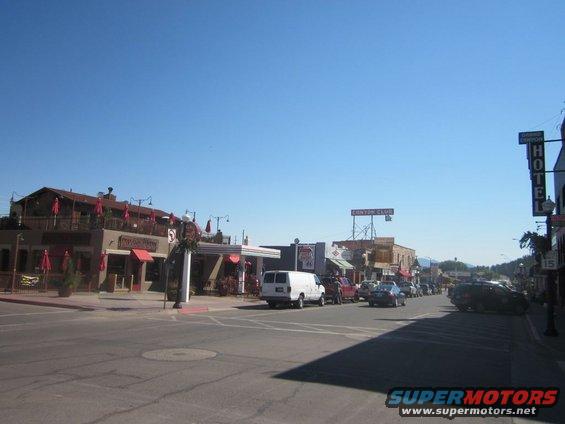 Street view of a town with various cars and buildings under a clear blue sky
