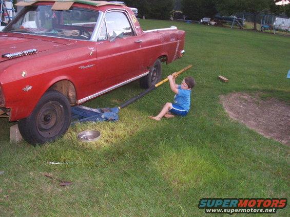 Red 1966 Ford Ranchero being jacked up by a child