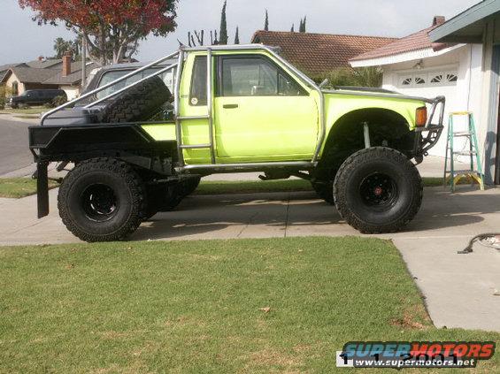 Lime green pickup truck with flatbed, roll cage, and large off-road tires parked on a driveway