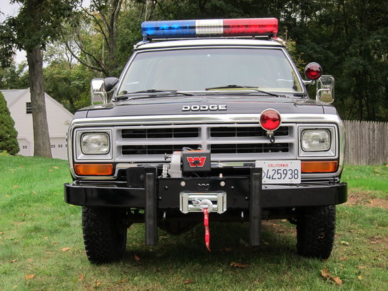 Front view of a black 1987 Dodge Ram pickup truck with emergency lights and a winch