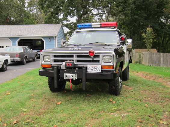 Black police truck with light bar and winch, front view. License plate 425938