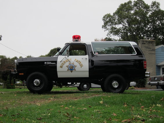 Black and white Dodge Ramcharger with "HIGHWAY PATROL" text and a red light bar