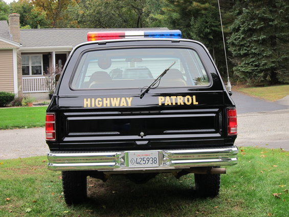 Rear view of black SUV with 'HIGHWAY PATROL' text and light bar