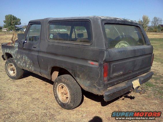Black 1978 Ford Bronco with faded paint, seen from the rear-right quarter angle