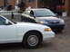 1997 Ford Crown Victoria - A white Ford Crown Victoria is parked next to a blue Toyota Corolla.