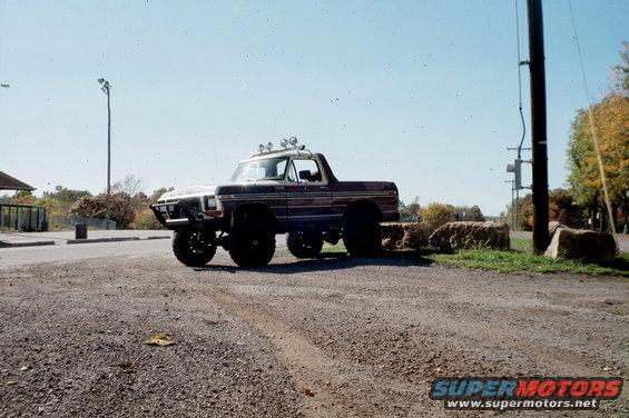 Lifted 1978 Ford Bronco with aftermarket bumper and roof lights parked on gravel