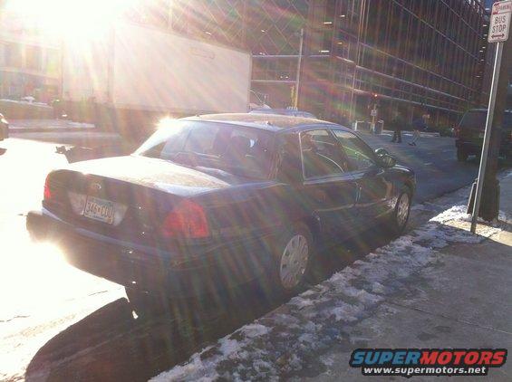 Dark 2003 Ford Crown Victoria parked on a snowy street, rear view