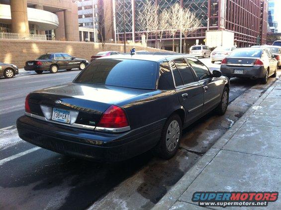 Black 2003 Ford Crown Victoria parked on street, rear view. Another car is parked behind it