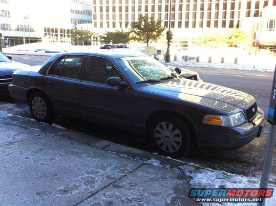 Dark gray 2003 Ford Crown Victoria parked curbside, front quarter view, with snow on the ground