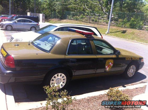 Gold and black State Trooper car, side view. 2003 Ford Crown Victoria