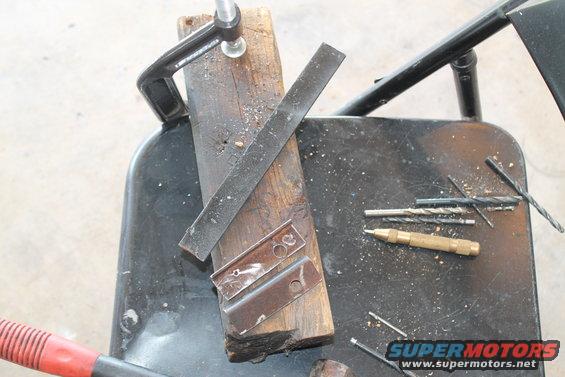 Metal brackets clamped to wood with drill bits and a punch nearby