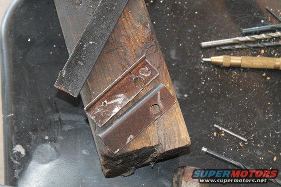 Metal brackets on wood block with drill bits and center punch