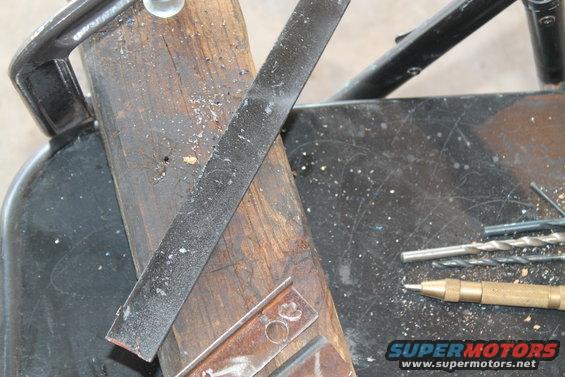 Workbench with a file, drill bits, and a center punch. Supermotors.net logo visible