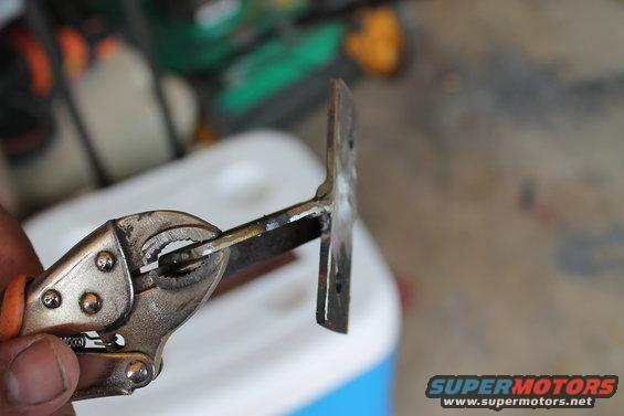 Locking pliers gripping a metal bracket with two holes