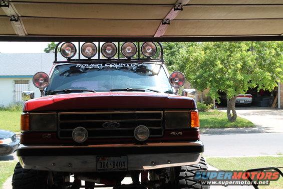 Red 1990 Ford Bronco with roof-mounted lights and "ROUGH COUNTRY" decal