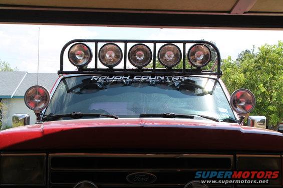 Red Ford truck front view with a "Rough Country" light bar and two side lights