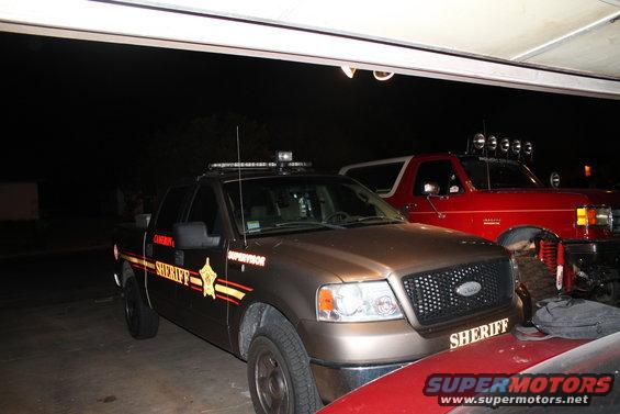 Red Ford Bronco with a light bar on the roof, seen from the front-right