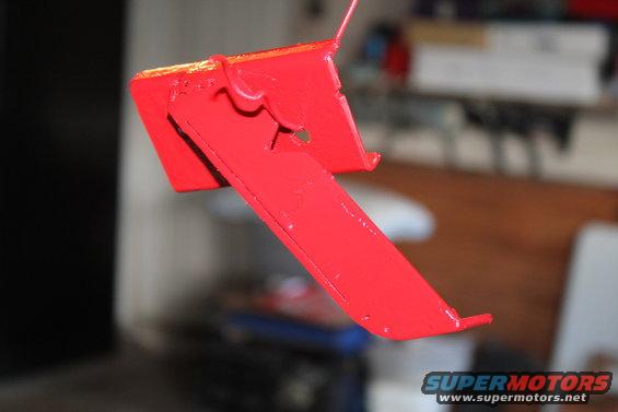 Red painted metal bracket with a hook, hanging from a wire
