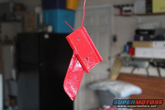 Red painted metal bracket hanging by wire