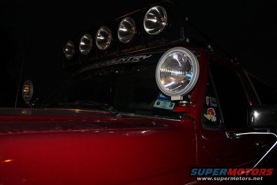 1990 Ford Bronco with roof-mounted light bar and a large auxiliary light on the A-pillar
