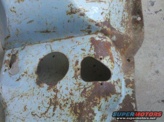 Rusted light blue metal panel with two circular openings and a triangular opening