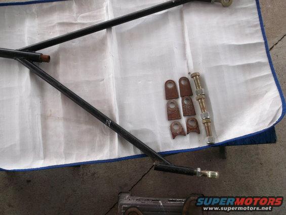 Black metal suspension arms and rusty metal brackets with bolts on a white cloth
