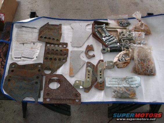 Bunch of rusty metal brackets, bolts, nuts, and some paperwork laid out on a blue tarp