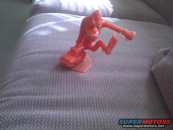 Orange toy figure on a couch with Supermotors logo