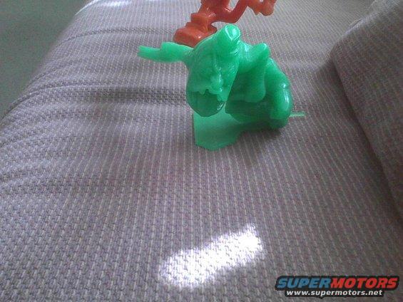 Green and orange toy figures on a textured couch with a sunbeam