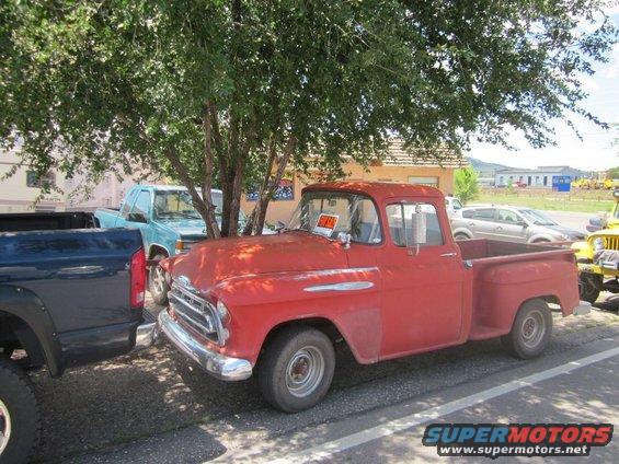 Red 1955 pickup truck with chrome trim and a 'For Sale' sign